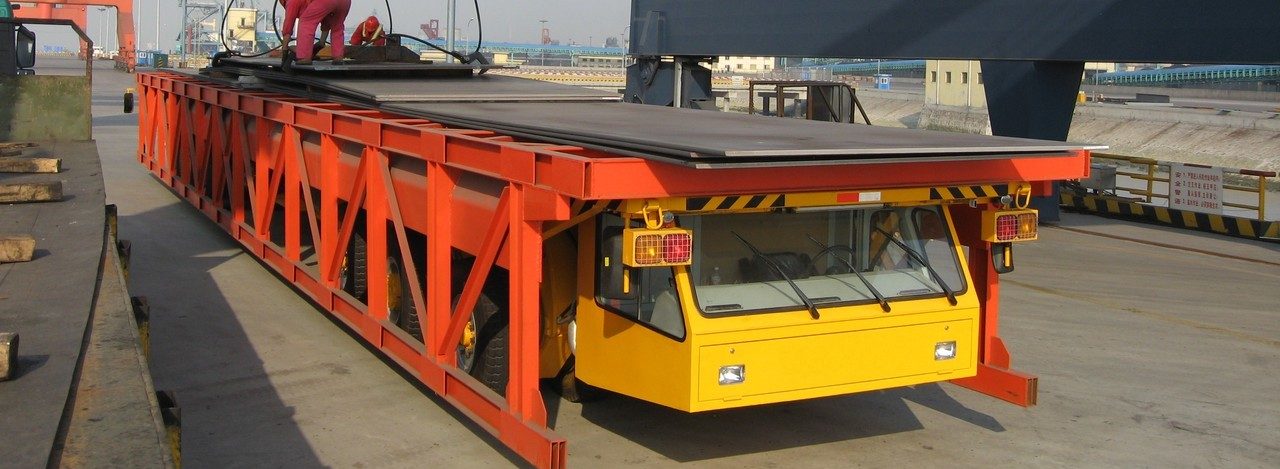 Steel mill transporter carrying a steel slab on a platform above the axle line